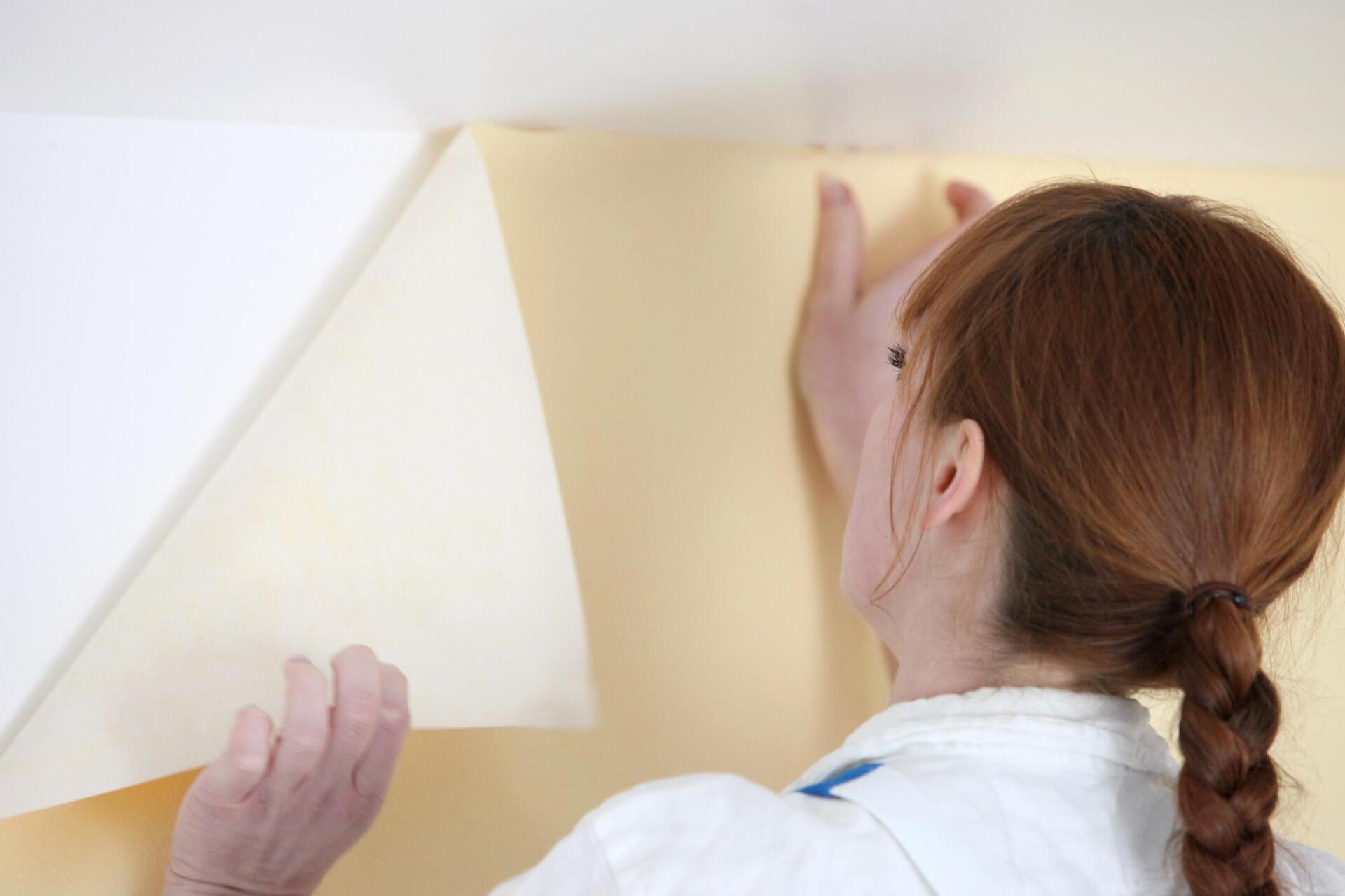 woman removing the wallpaper